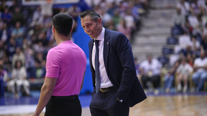 Entrenador del Monbus Obradoiro conversando con un árbitro durante un partido de baloncesto.