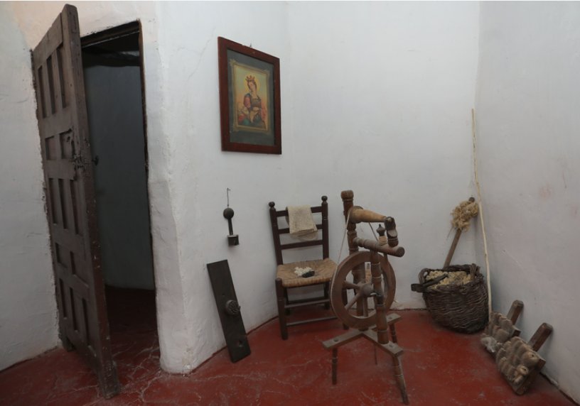 Interior de La Casa del Abuelo con objetos antiguos y una silla de madera