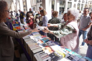 Personas comprando libros en la Calle Mayor de Palencia durante el Día del Libro