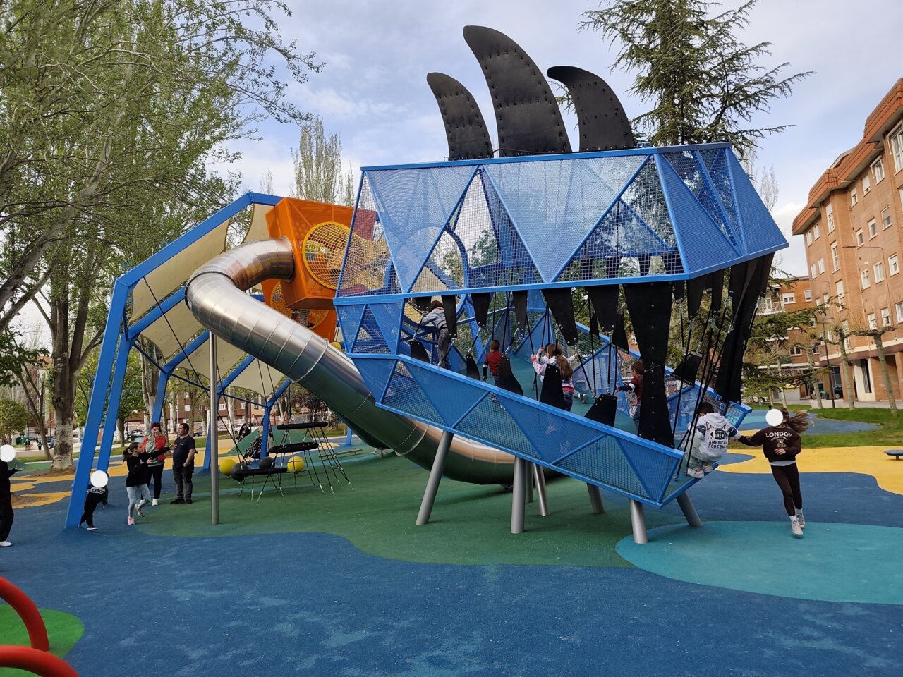 Niños jugando en un parque con un gran tobogán azul