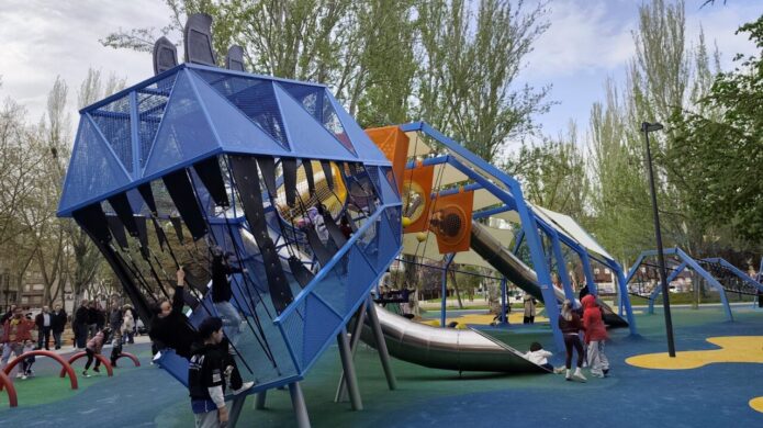 Niños jugando en un parque infantil renovado con estructuras modernas