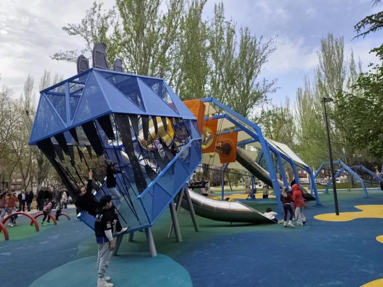 Niños jugando en un parque infantil renovado con estructuras modernas