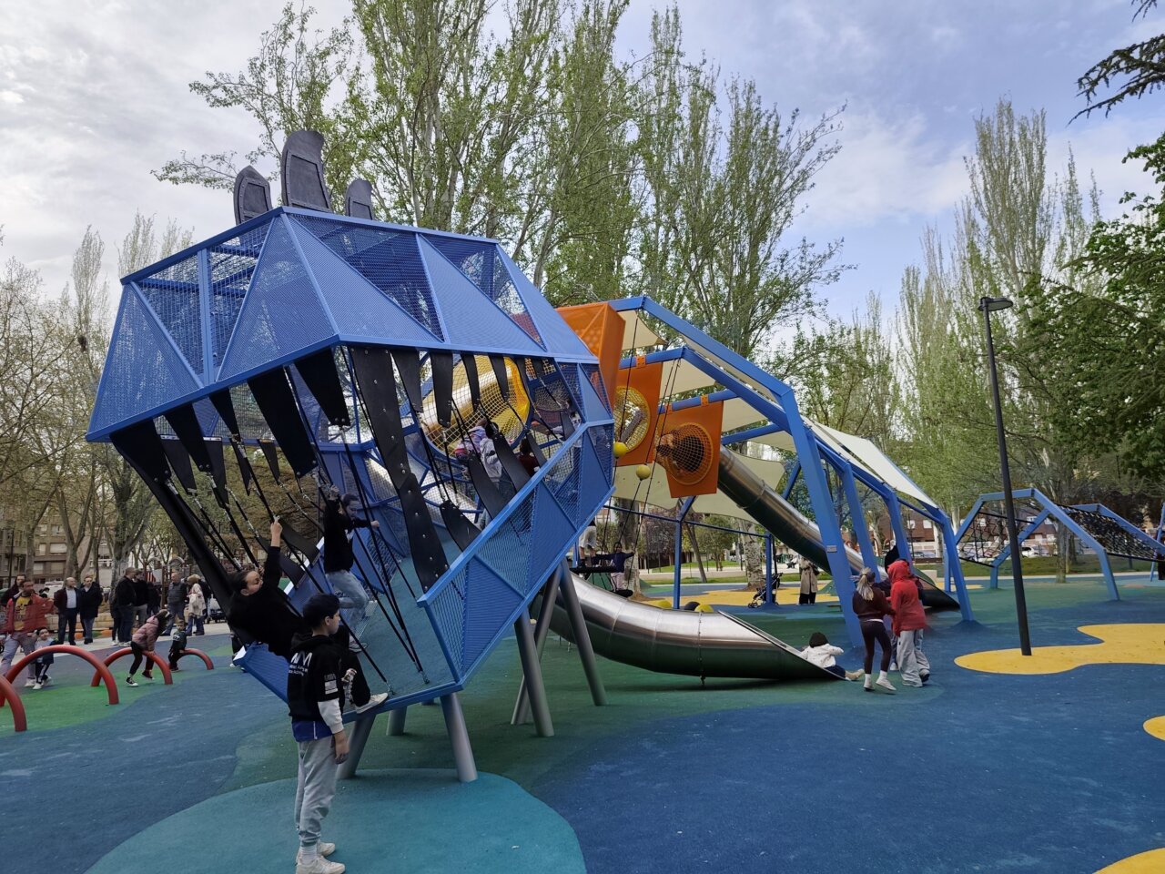 Niños jugando en un parque infantil renovado con estructuras modernas