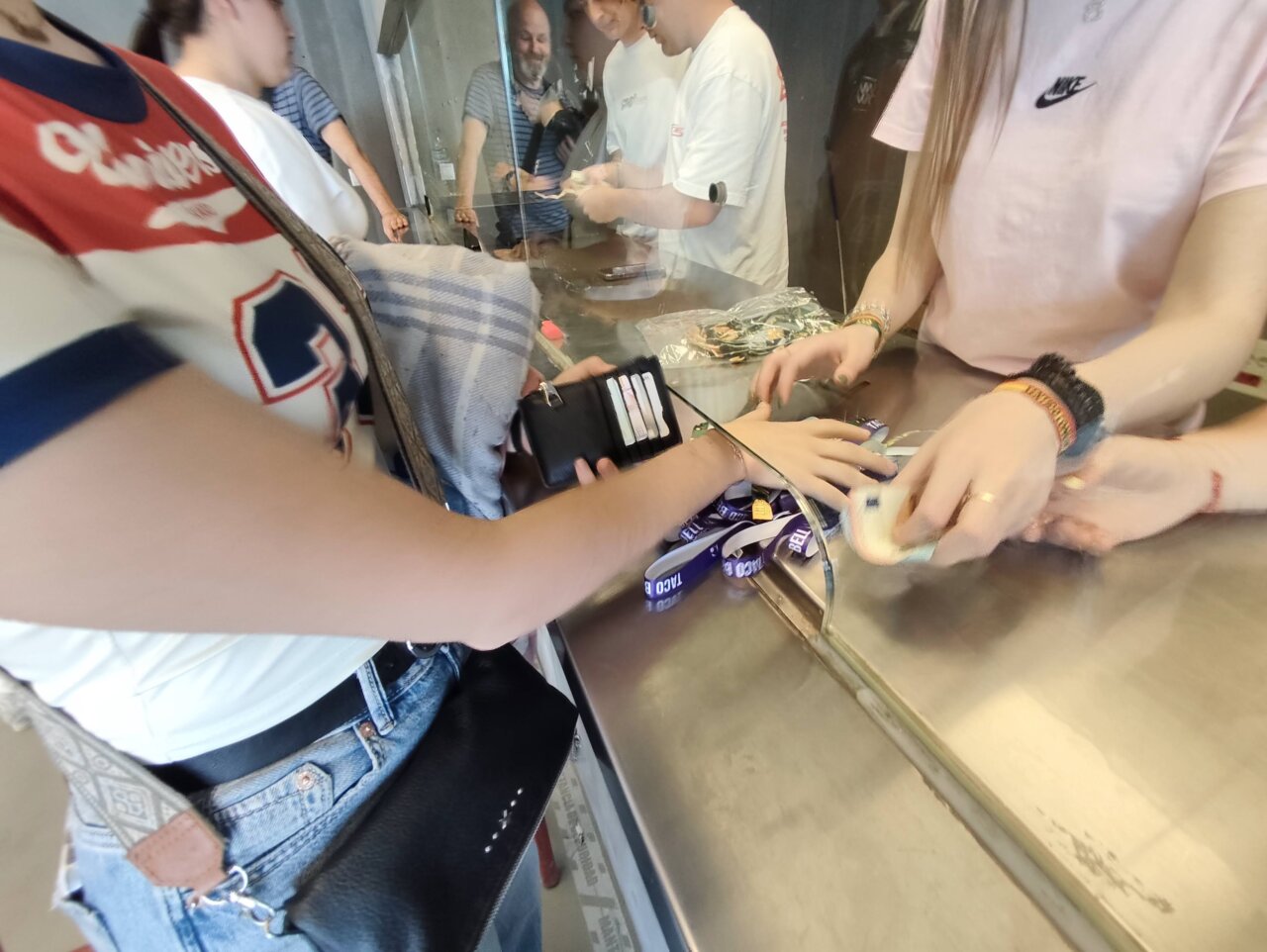 Personas comprando entradas en taquilla con pulseras en la mano