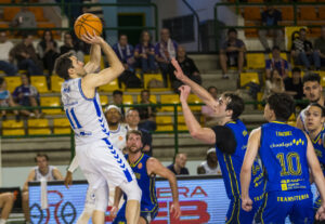 Jugador lanzando a canasta durante un partido de baloncesto