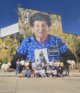 Mural de una mujer mayor con flores y vecinos en Brañosera