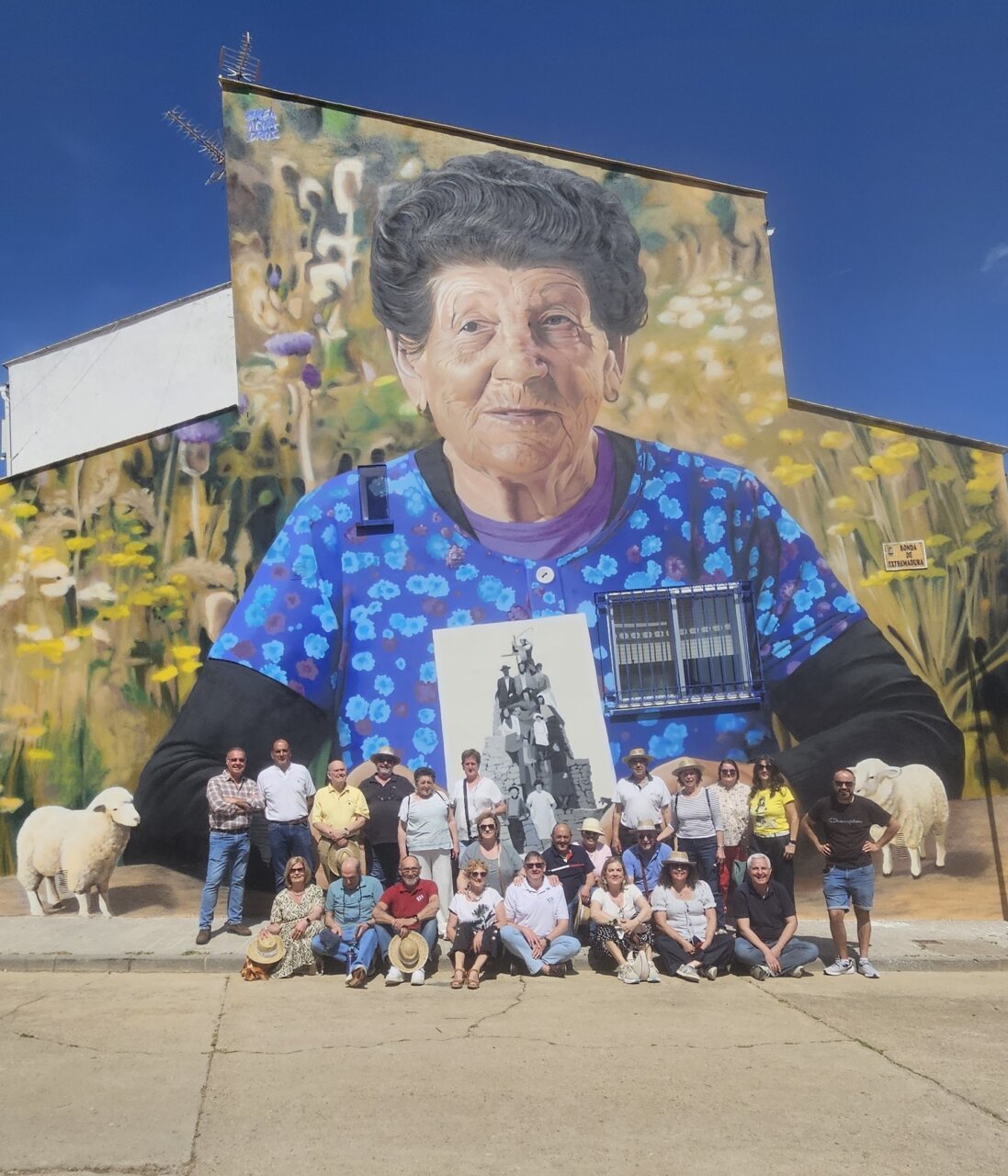 Mural de una mujer mayor con flores y vecinos en Brañosera