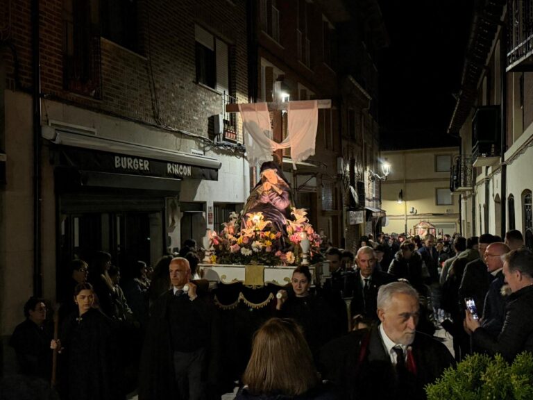 Procesión de Semana Santa en Carrión de los Condes con participantes y un paso religioso.