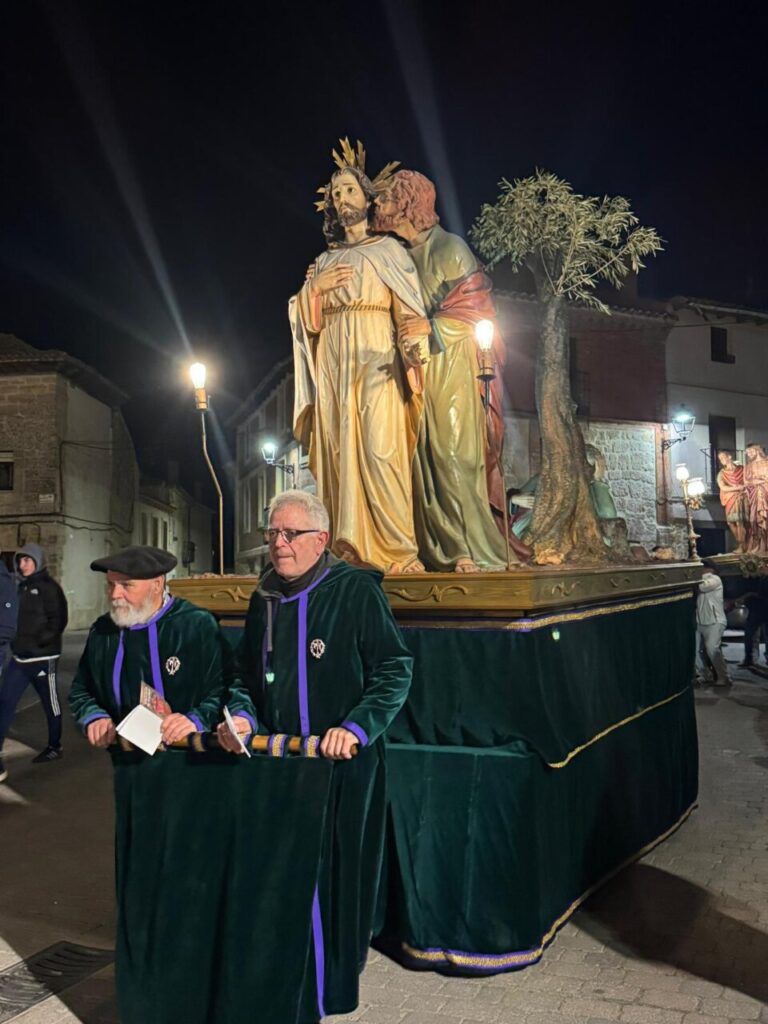 Dos hombres sosteniendo un paso religioso durante la procesión del Jueves Santo en Astudillo.