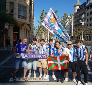 Grupo de aficionados del CD Becerril con bufandas y bandera en Sevilla