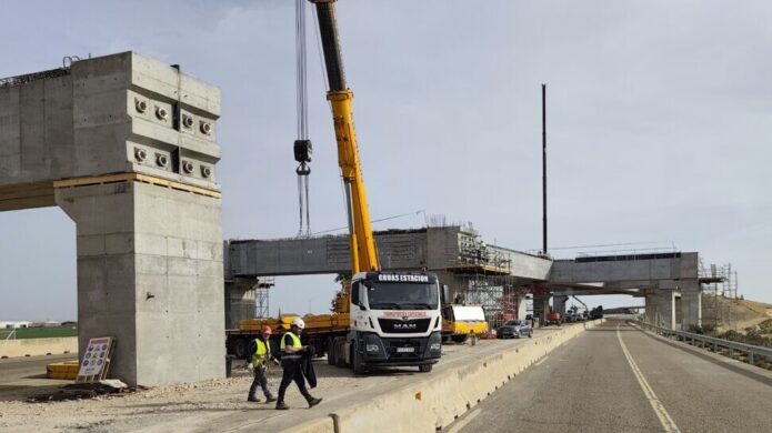 Obras en la A-67 con grúas y trabajadores en el viaducto