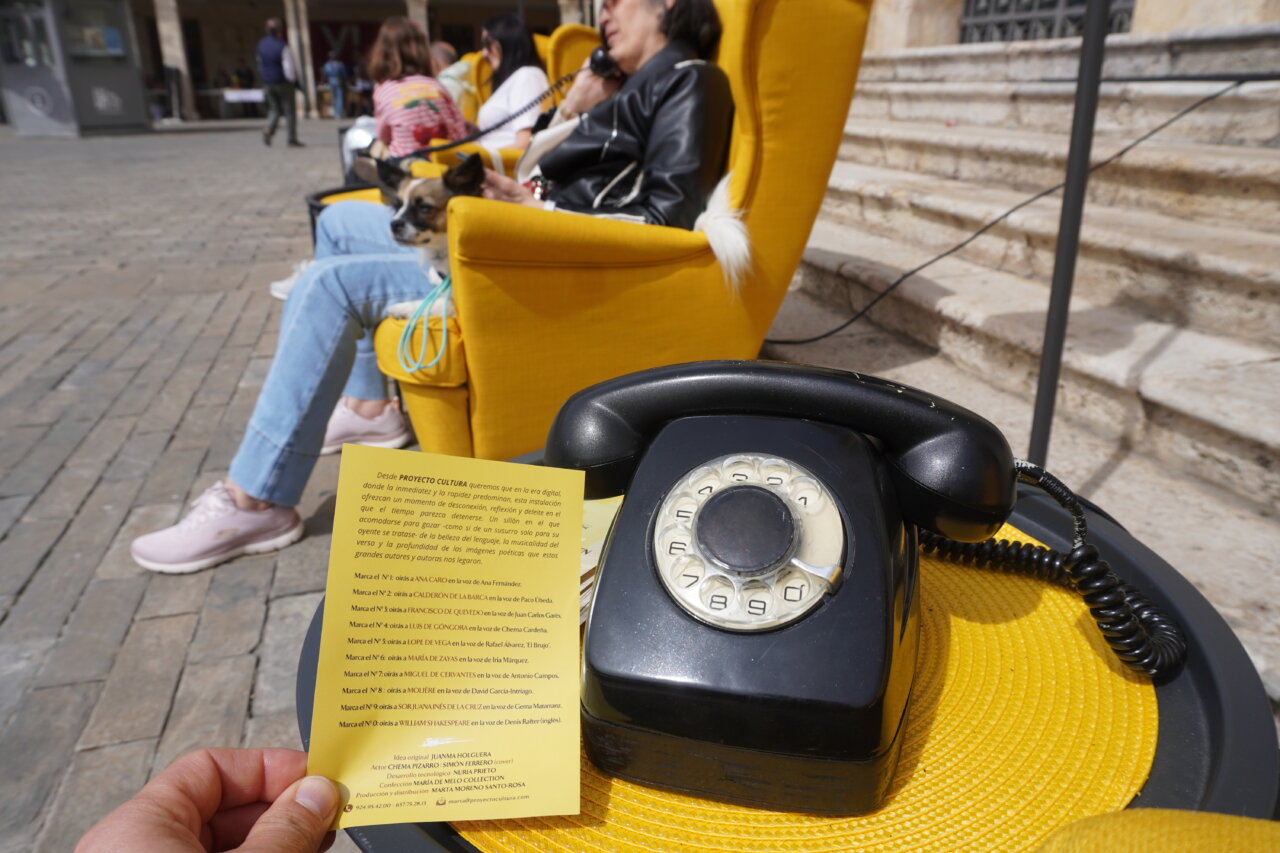Teléfono antiguo sobre mesa amarilla con sillones en la plaza Mayor