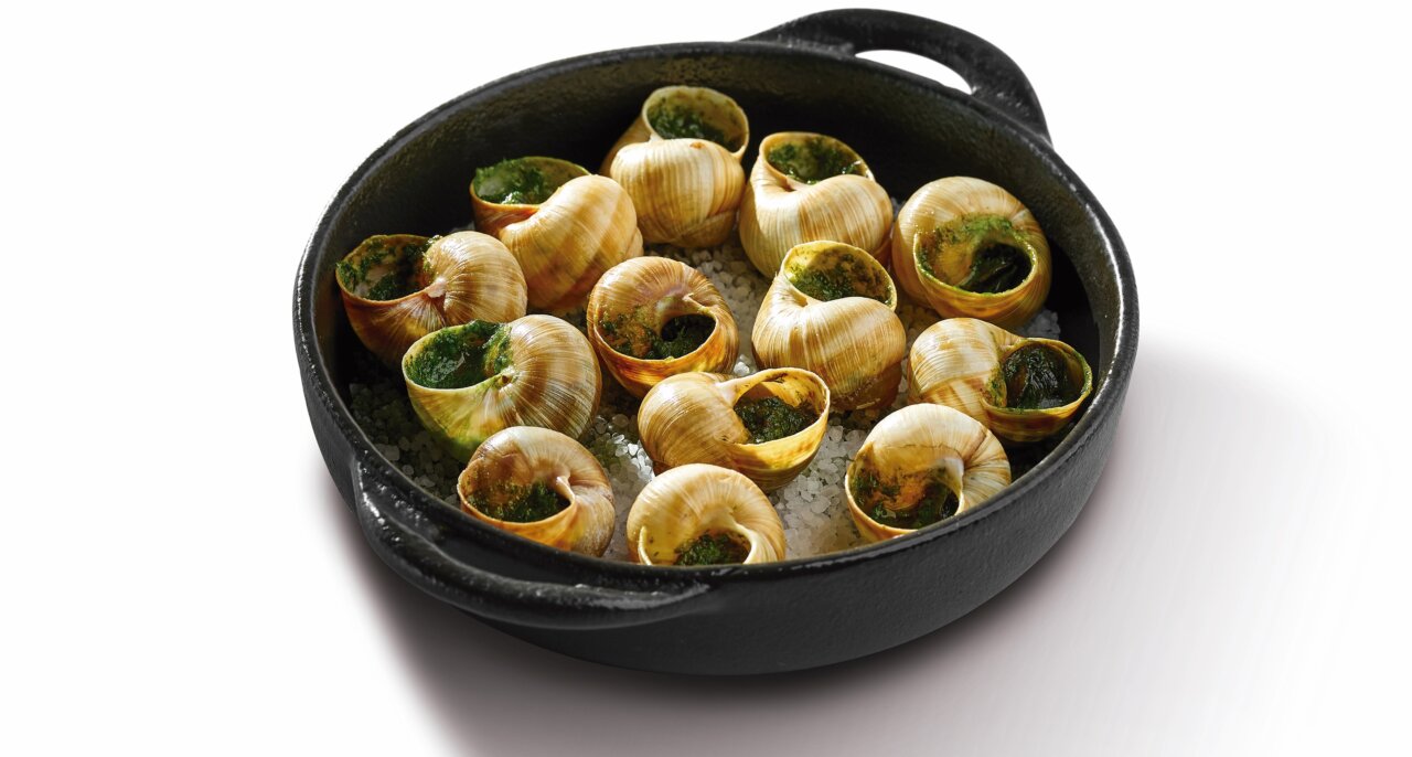 Plato de caracoles preparados con hierbas en una cazuela