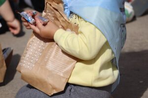 Niño sosteniendo bolsas de pan y quesillo en una actividad escolar