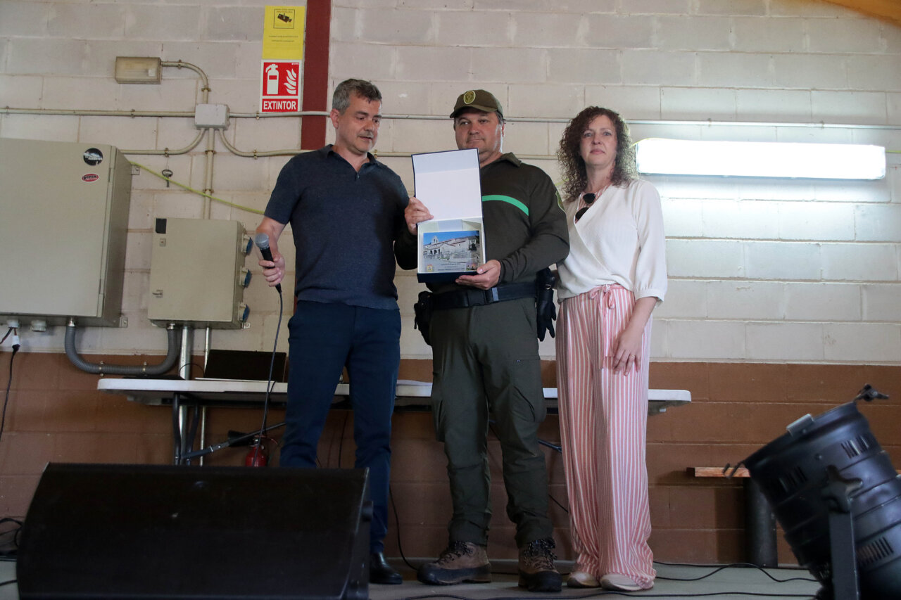 Tres personas en un evento de homenaje a brigadas forestales