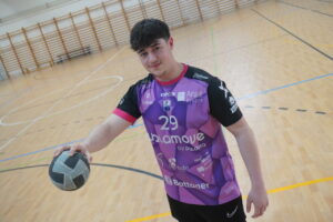 Joven jugador de balonmano sosteniendo un balón en una cancha