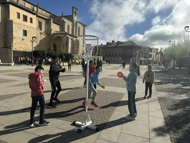 Niños jugando baloncesto en una plaza durante un evento deportivo