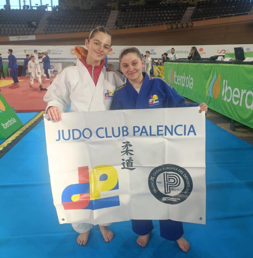 Dos jóvenes del Judo Club Palencia sosteniendo una bandera en el campeonato escolar