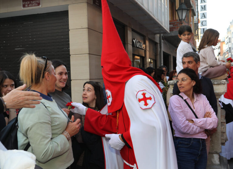 Cofrade interactuando con mujeres durante la procesión de la Soledad en Palencia