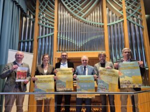 Presentación del evento Folkloreando 2026 con varios participantes mostrando carteles.