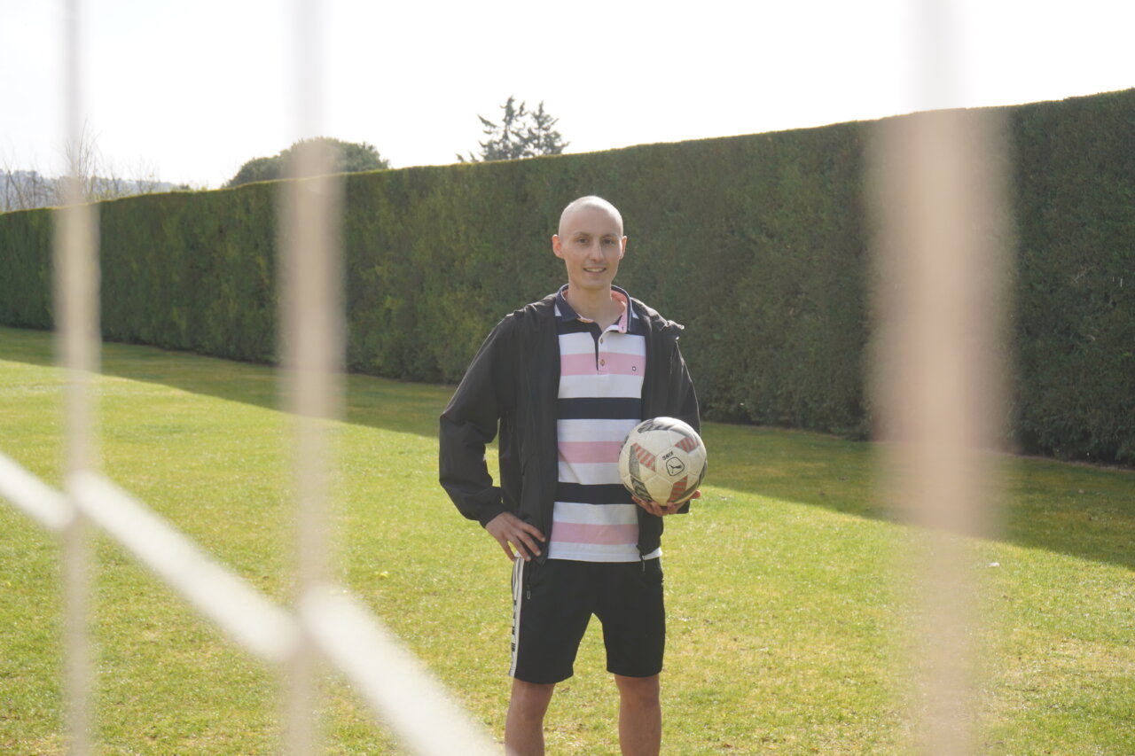 Mario Martínez, jugador de fútbol, sonríe sosteniendo un balón en el campo.