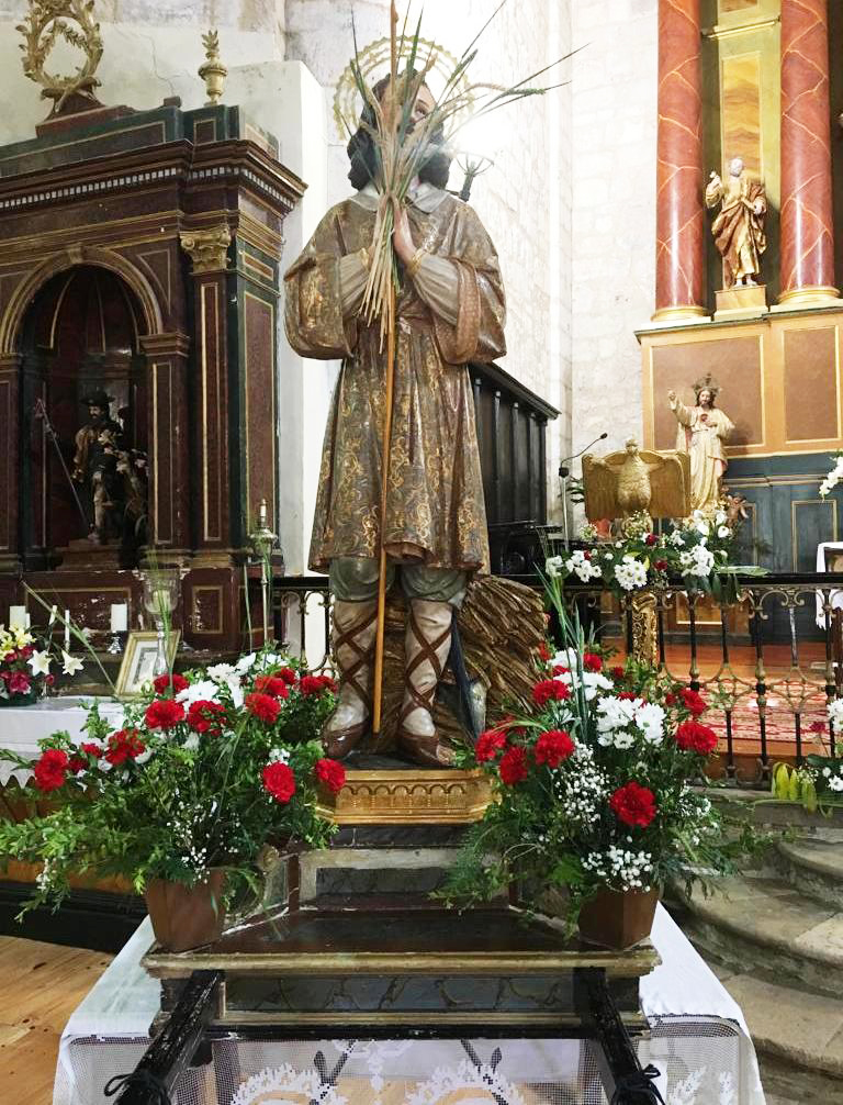 Estatua de San Isidro en la iglesia de Torquemada decorada con flores.