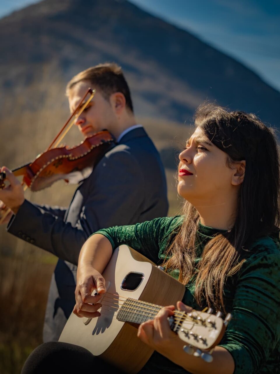 Músicos de Terra Sigilata tocando instrumentos en un paisaje montañoso.
