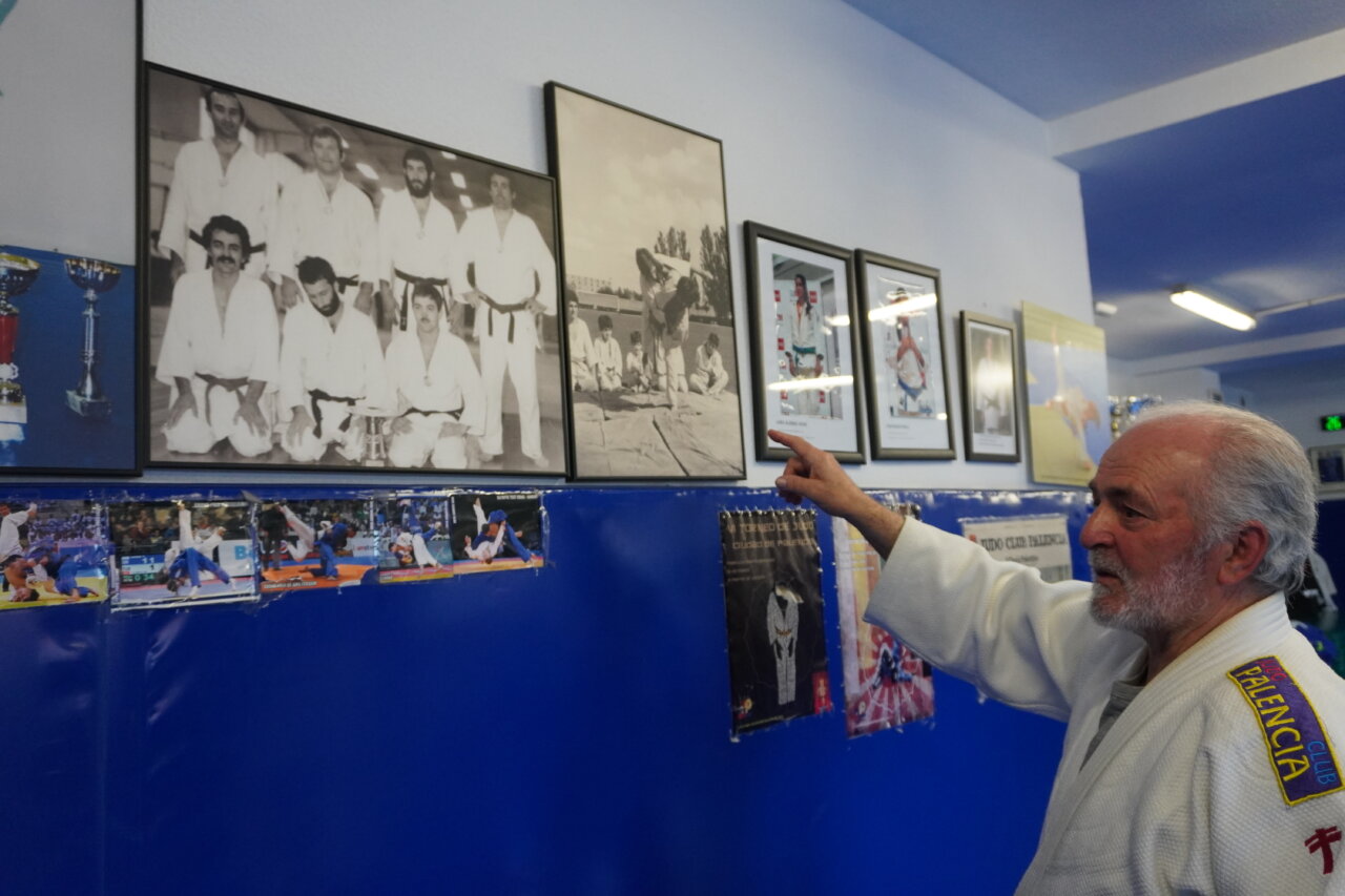 Entrenador de judo señalando fotos en la pared del gimnasio