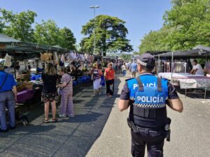 Agente de policía supervisando un mercadillo en Palencia con vendedores y compradores.