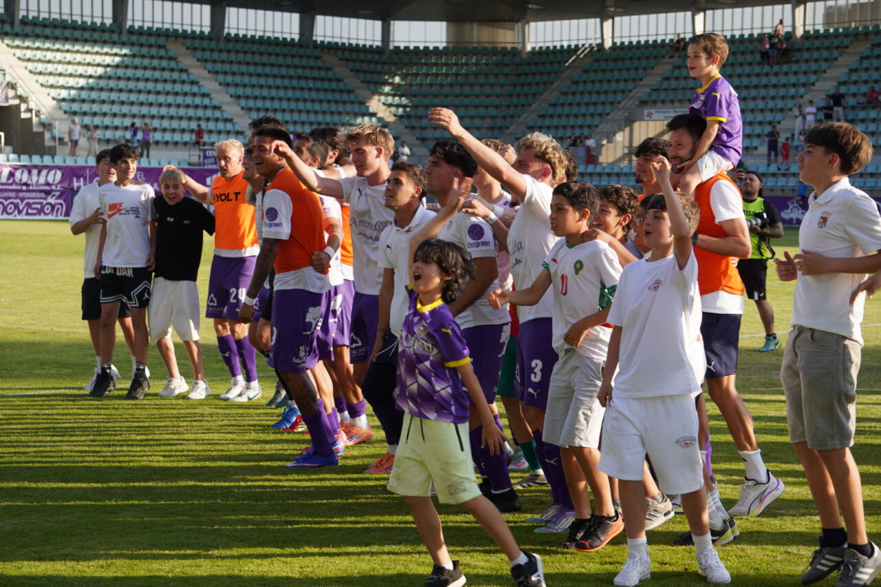 Jugadores y aficionados celebrando tras un partido de fútbol en Palencia.