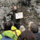 Guía explicando formaciones geológicas a un grupo en Aguilar de Campoo