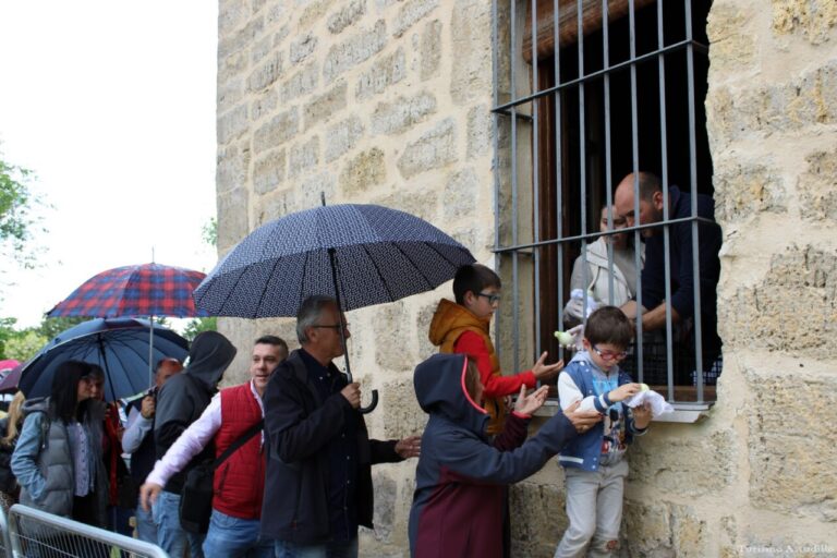 Personas en fila bajo paraguas recibiendo alimentos en Astudillo