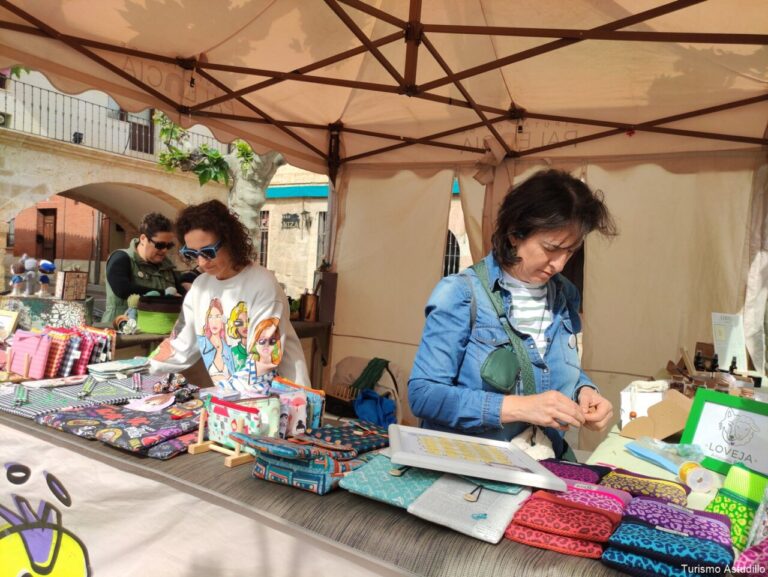 Mujer organizando productos en un mercado artesanal durante el Voto Villa en Astudillo