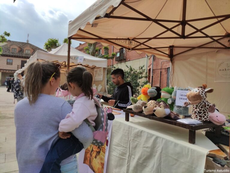 Mujer con niña en brazos en un mercado de artesanía en Astudillo