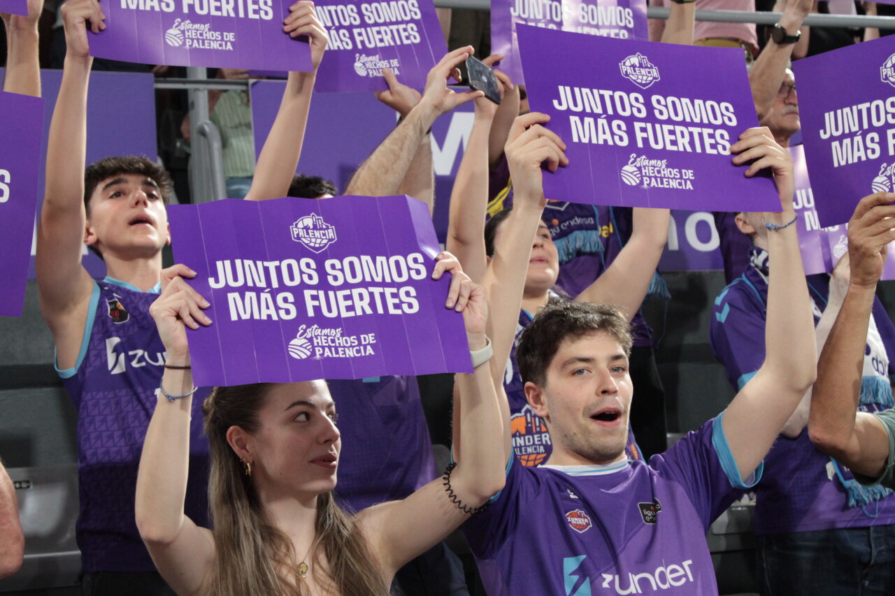 Aficionados sosteniendo carteles en un evento deportivo en Palencia.
