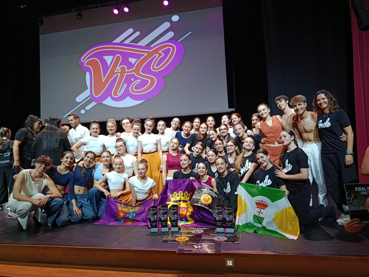 Grupo de estudiantes de danza de la Escuela Smile celebrando premios en el escenario.