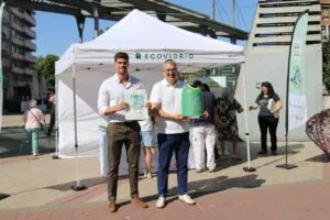 Dos hombres sosteniendo carteles sobre reciclaje de vidrio en un evento