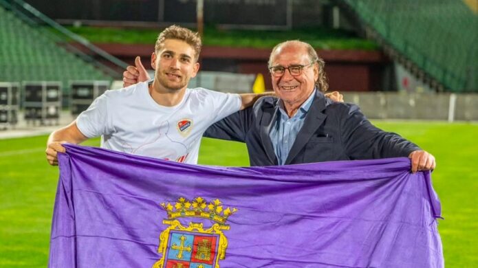 Abel Pascual celebrando con un hombre mayor y una bandera en el campo de fútbol