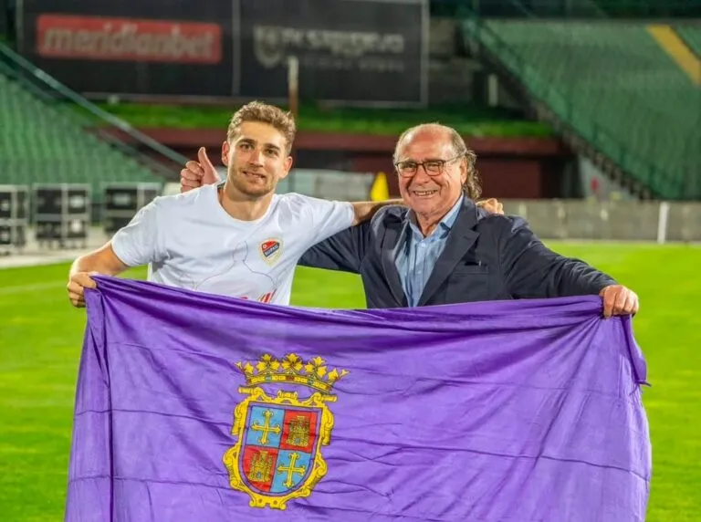 Abel Pascual celebrando con un hombre mayor y una bandera en el campo de fútbol