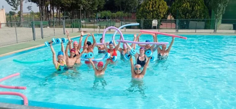 Grupo de personas realizando actividad física en una piscina con flotadores