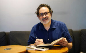 Adolfo Arranz dibujando en un cuaderno en un café