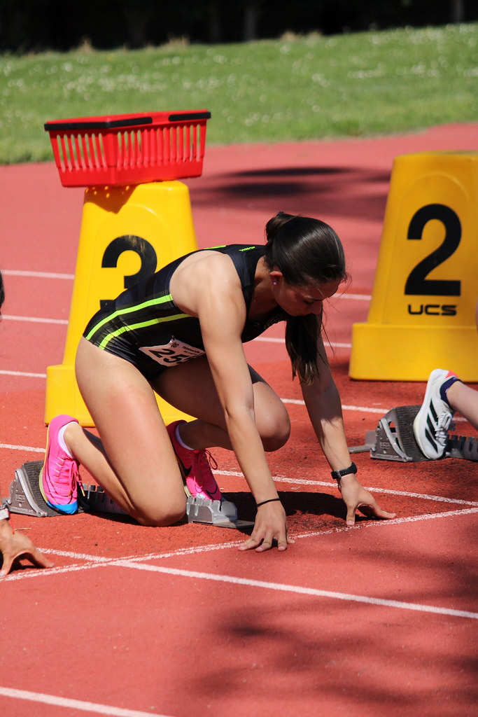 Atleta femenina preparándose para una carrera en el campo de atletismo.