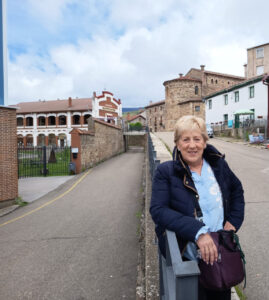 Mujer sonriente en Barruelo de Santullán con edificios históricos al fondo