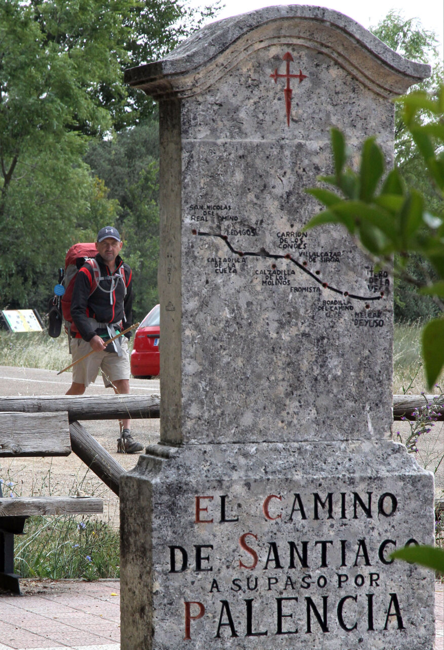 Peregrino caminando junto al monumento del Camino de Santiago en Palencia