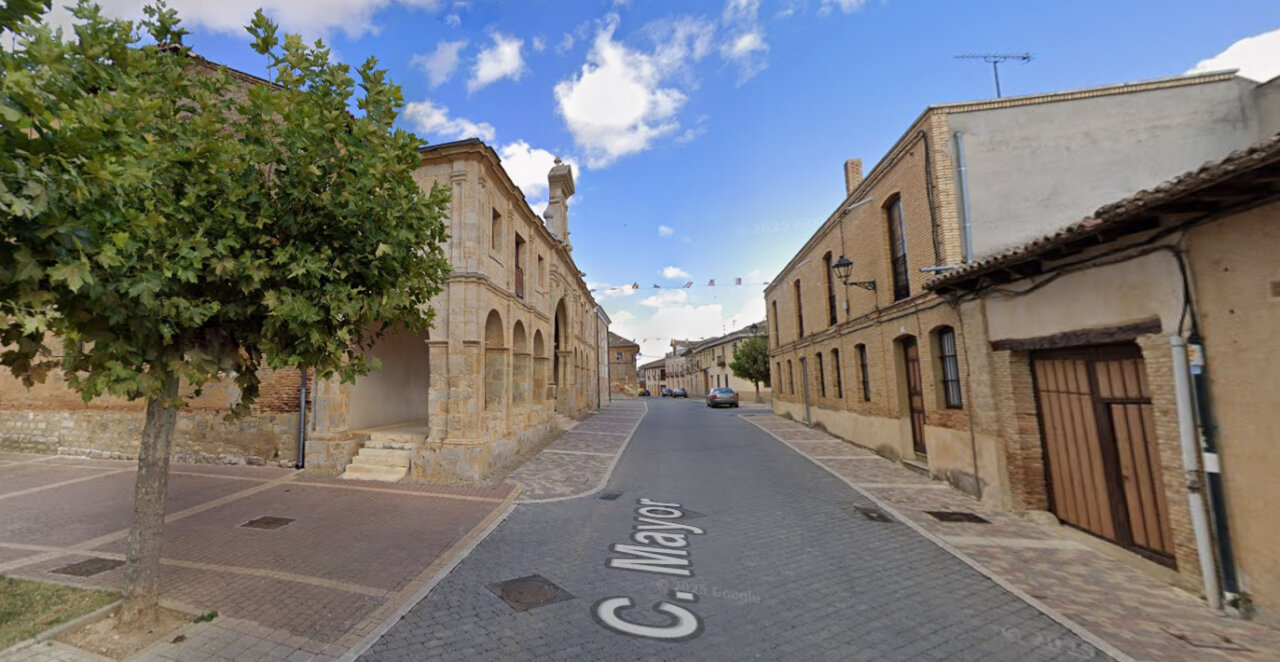 Vista de la calle Mayor en Fuentes de Nava con edificios y árboles