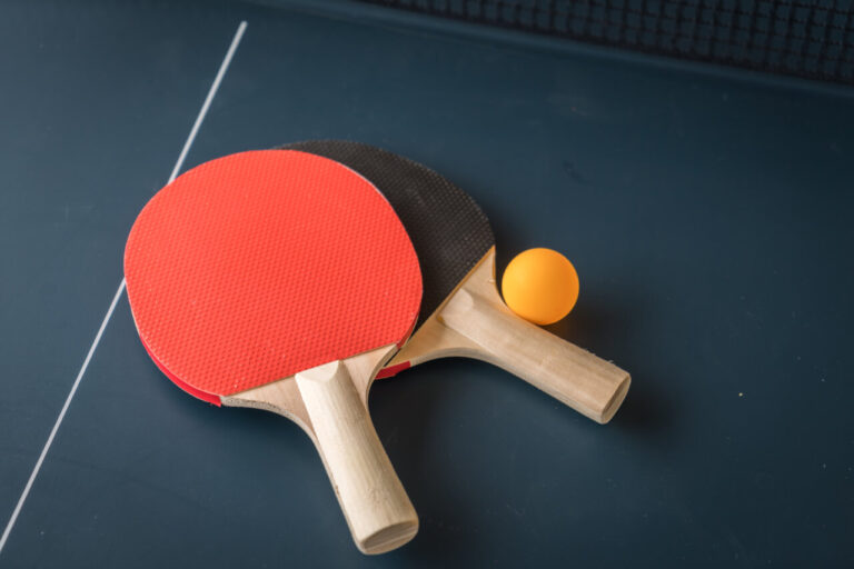 Raquetas de tenis de mesa y una pelota sobre una mesa