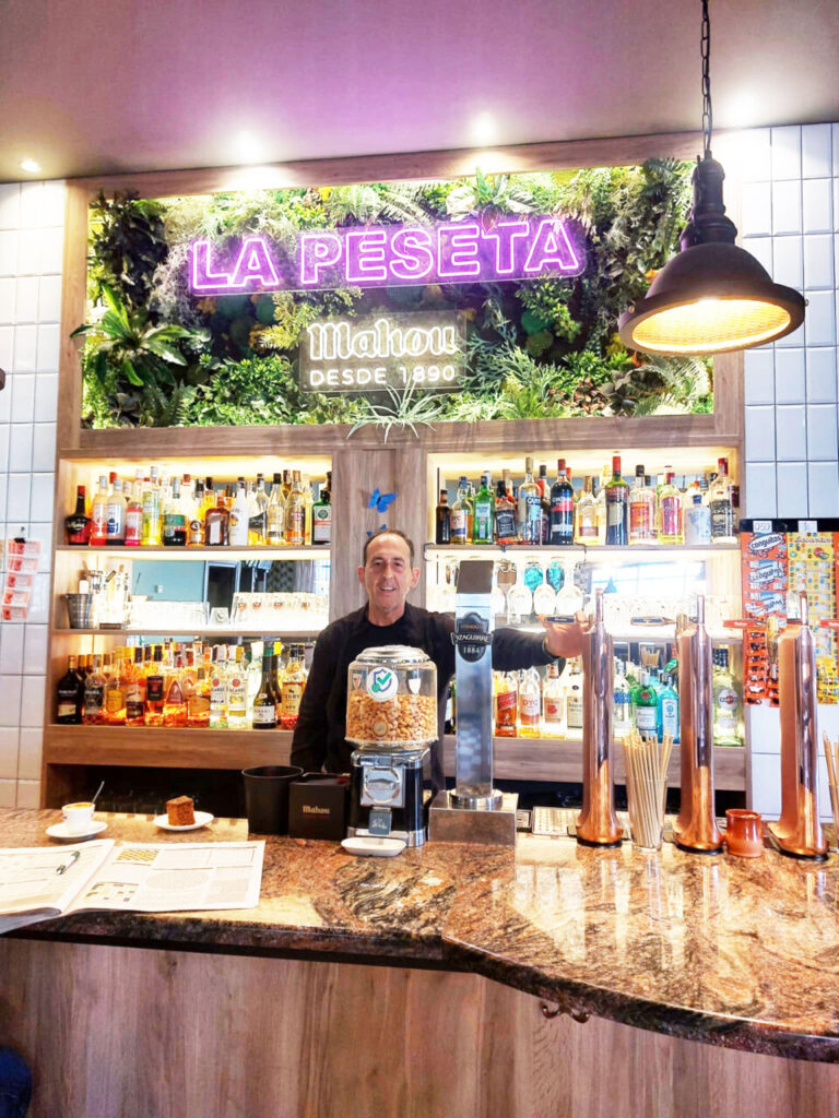 Carlos en la barra de Cervecería La Peseta con bebidas y decoración