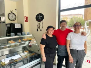 Tres personas sonriendo en un negocio de comida para llevar.