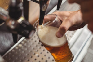 Barman llenando un vaso con cerveza artesanal desde una bomba de bar