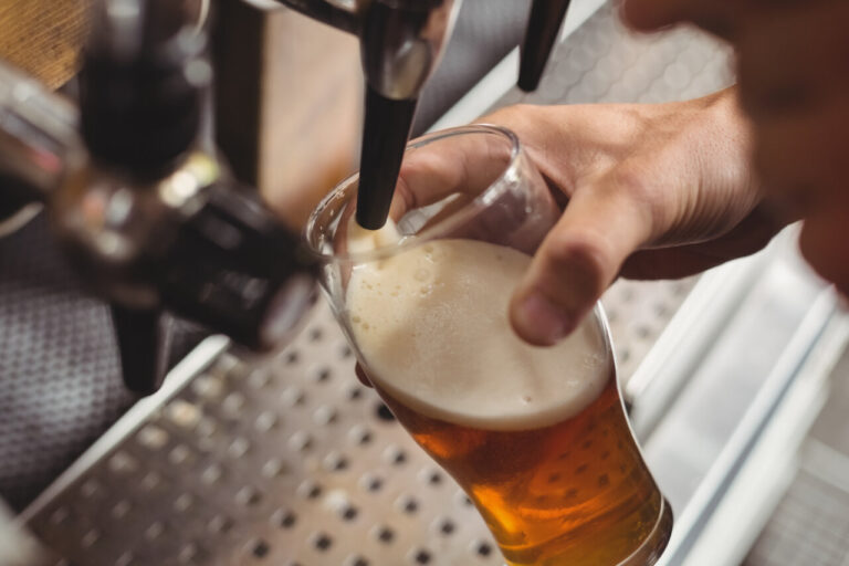 Barman llenando un vaso con cerveza artesanal desde una bomba de bar